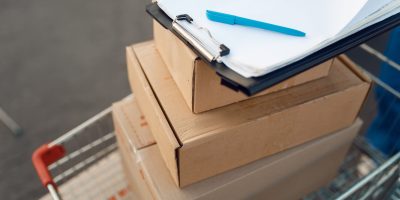 Parcel boxes and notebook in cargo cart, delivery service concept, delivering business, nobody. Cardboard packages, deliver, courier or shipping job